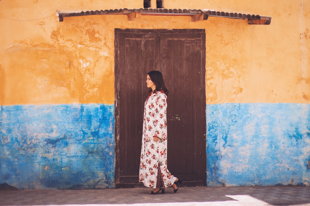 A Moroccan woman wearing a flowing linen kaftan browses a medina market, representing sustainable fashion in Morocco