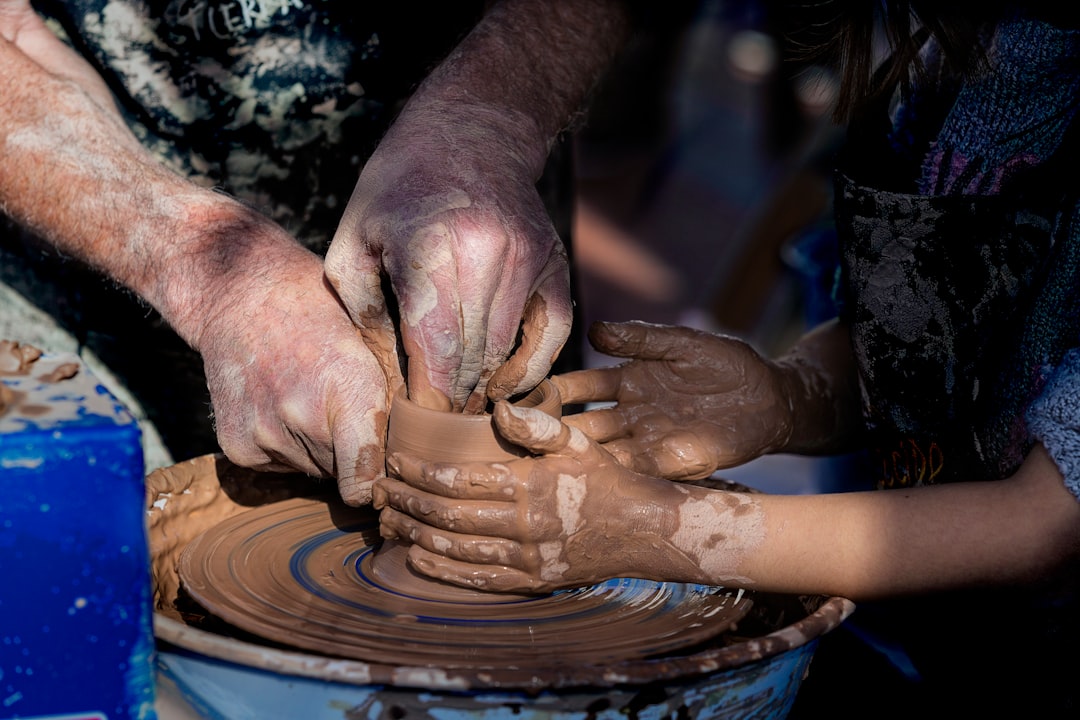 A mother and child shape clay together during a Morocco holiday craft workshop in a traditional Fes pottery studio