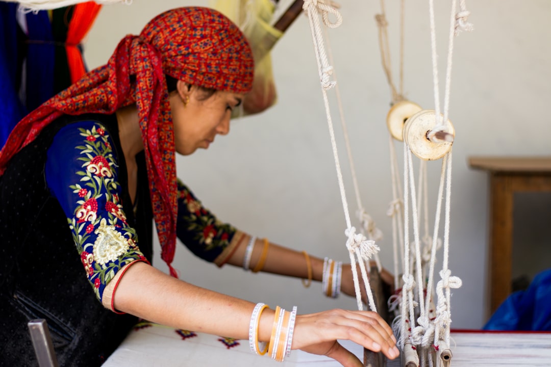 A member of a women cooperative in rural Morocco weaves a traditional textile at a shared workshop table