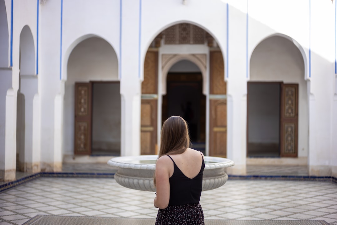 A woman sitting beside a central courtyard fountain in a traditional Moroccan riad, experiencing natural riad cooling.